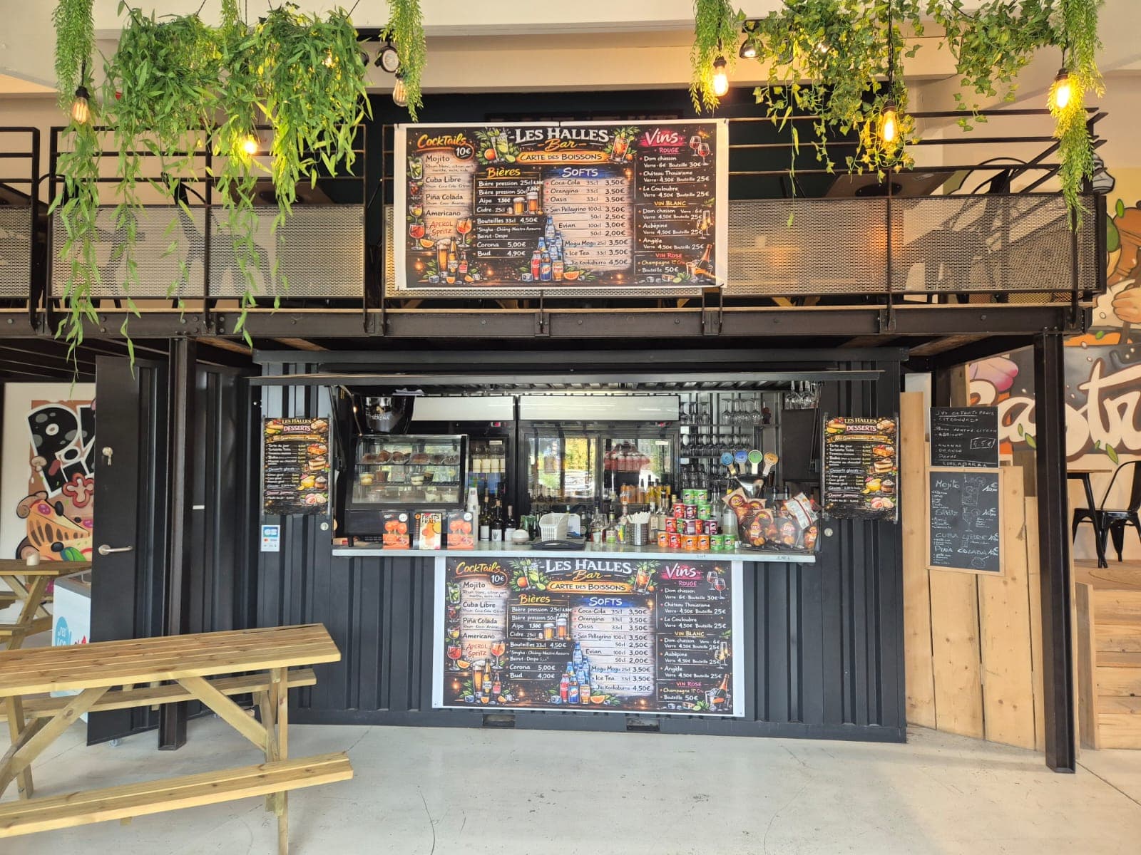 Comptoir du bar Les Halles, ardoises de cocktails, bières et vins, guirlandes lumineuses