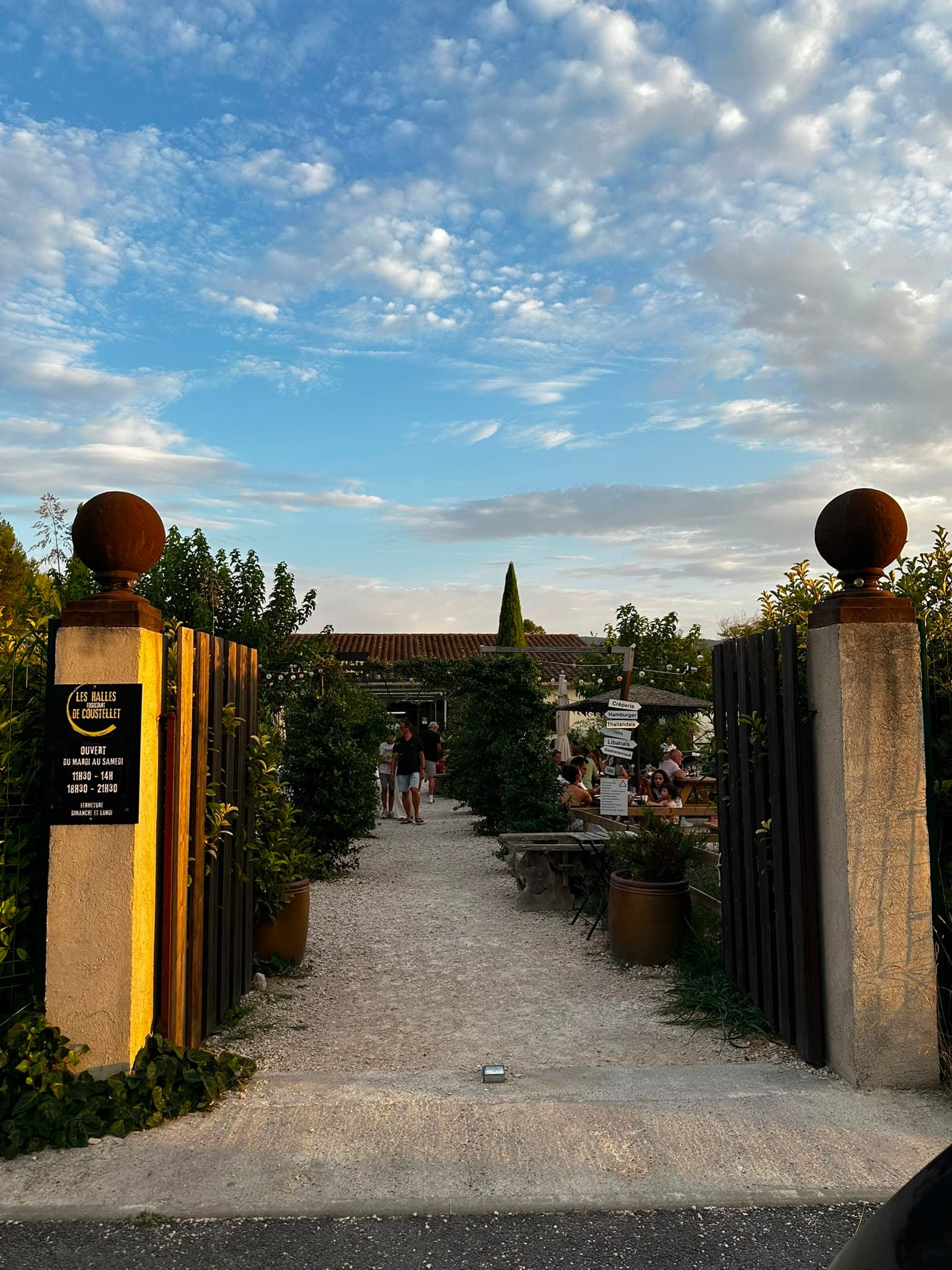 Entrée des Halles de Coustellet au coucher du soleil, guirlandes lumineuses et terrasse